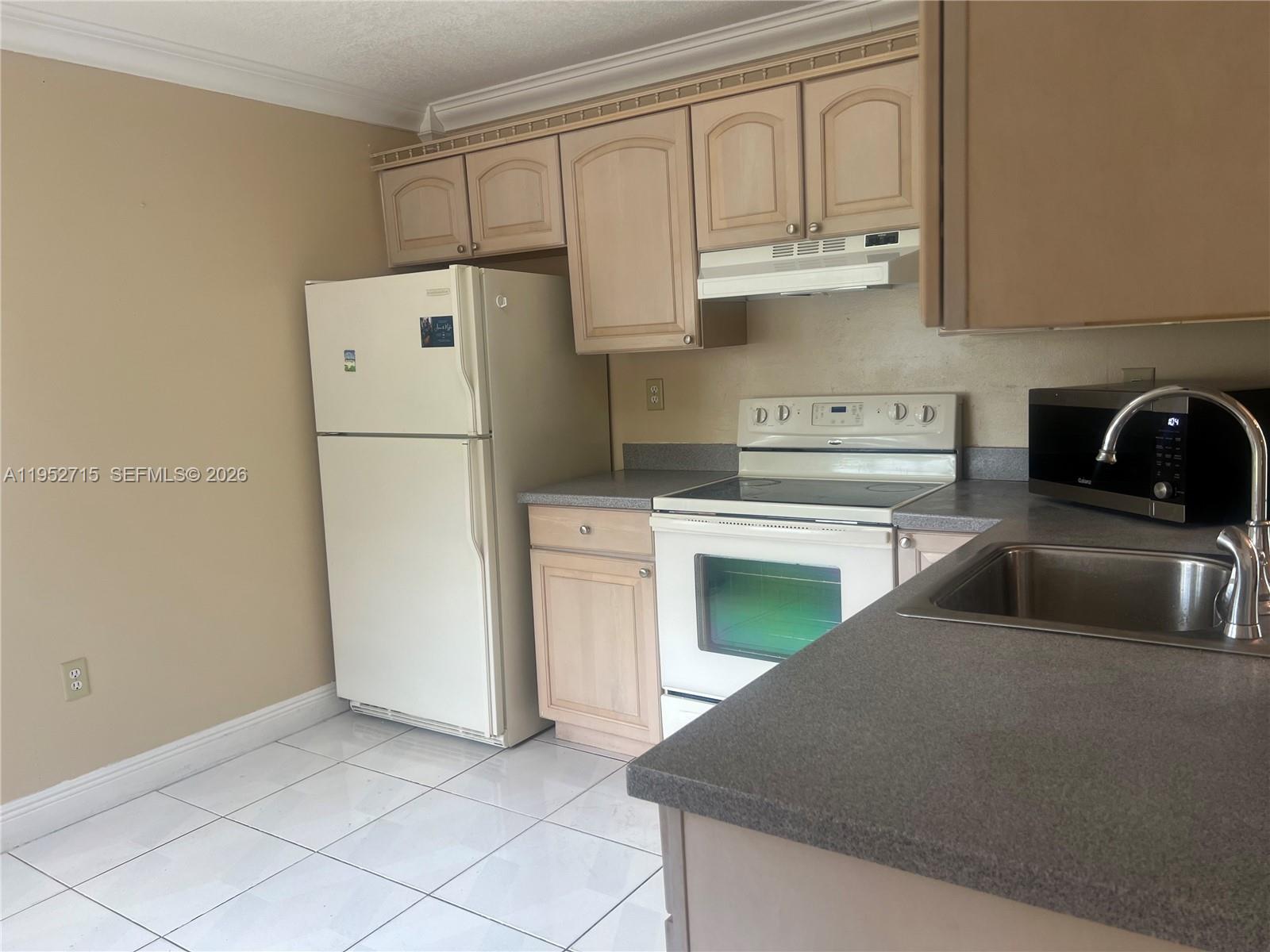 5827 Northwest 197th Terrace Hialeah, FL 33015 - Photo 15 of 30 a kitchen with cabinets a refrigerator and a stove top oven
