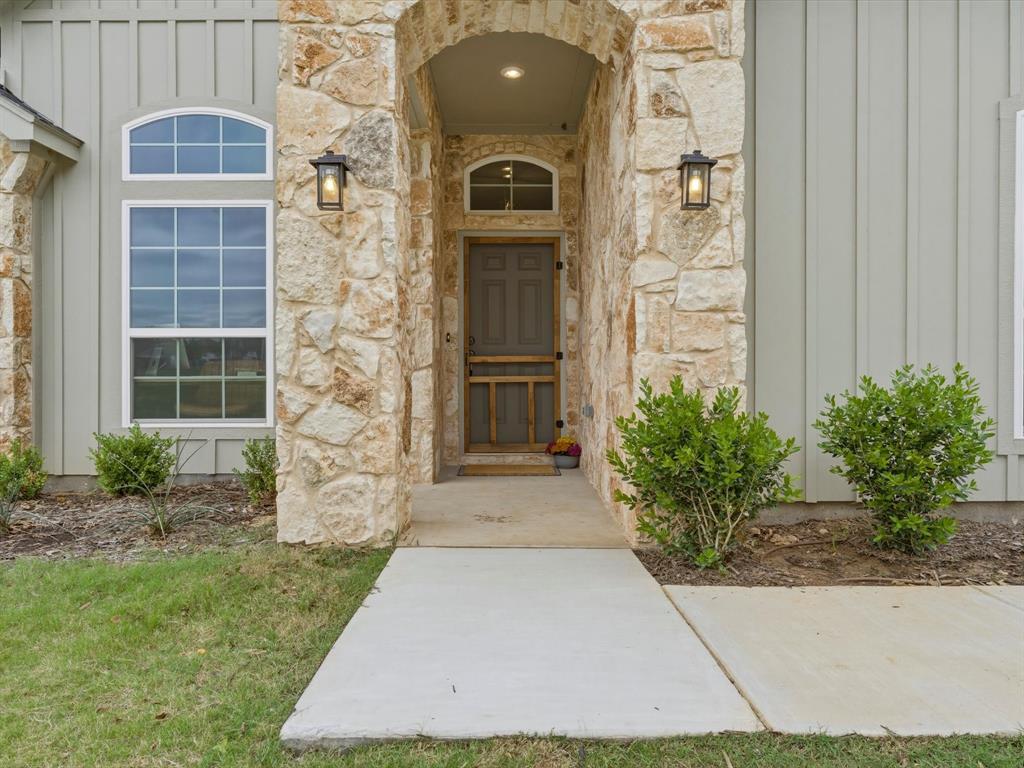 155 Rj Smith Drive Boyd, TX 76023 - Photo 2 of 37 Welcoming covered front porch featuring a self-closing screen door, perfect for enjoying peaceful country mornings.
