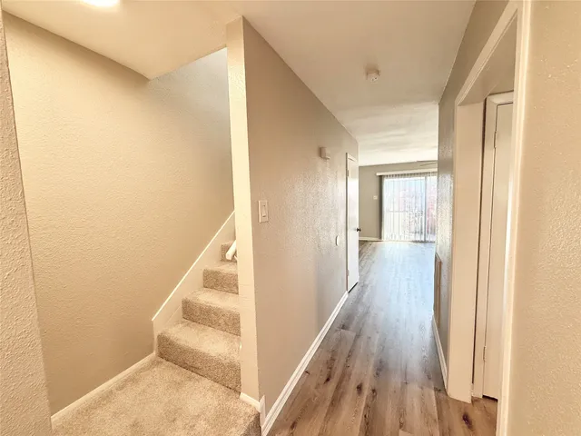 a view of a hallway with wooden floor and staircase