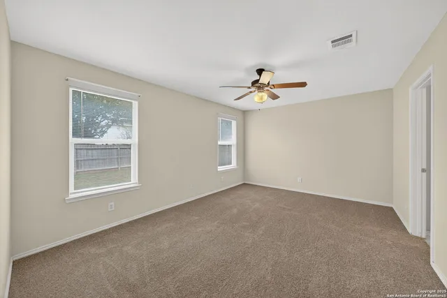 an empty room with a window and a ceiling fan