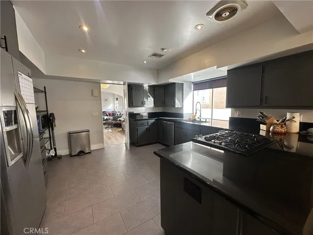 a kitchen with stainless steel appliances granite countertop a refrigerator a sink dishwasher a stove and a refrigerator with wooden floor