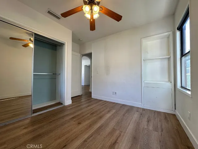 an empty room with wooden floor cabinet and windows