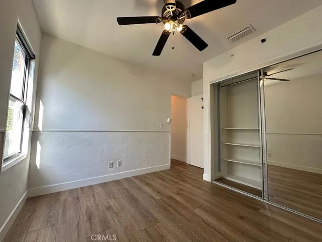 an empty room with wooden floor closet and windows