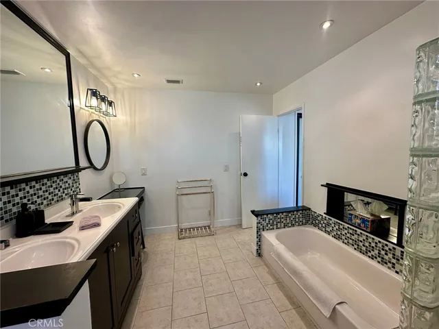 a spacious bathroom with a double vanity sink a mirror a bathtub and a shower