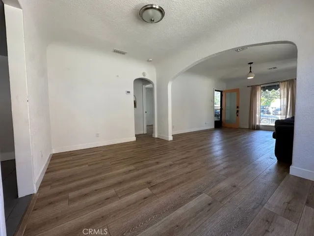 an empty room with wooden floor and windows