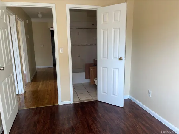 an empty room with wooden floor and a hallway