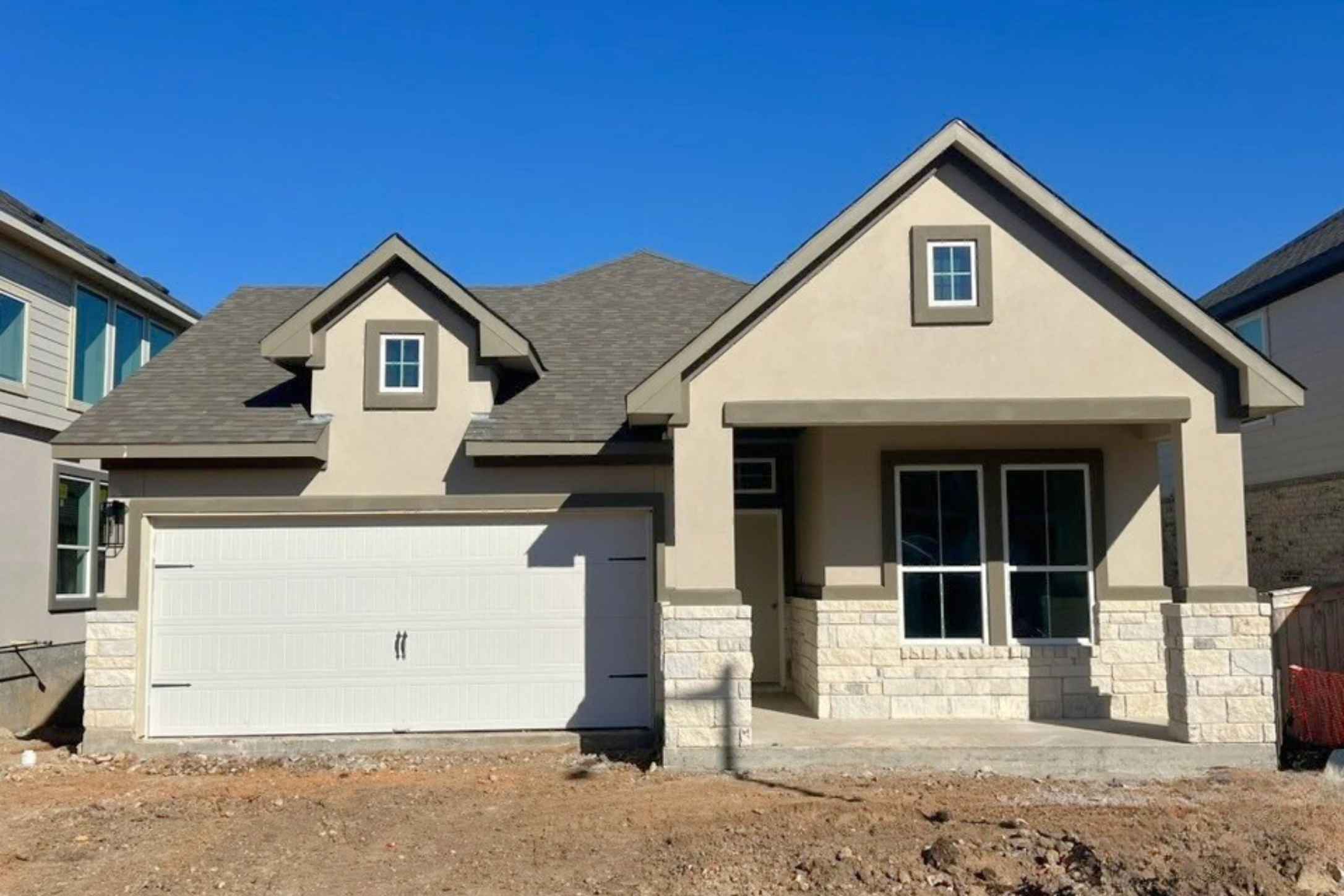 View of front facade with stucco siding, a garage, stone siding, and a porch