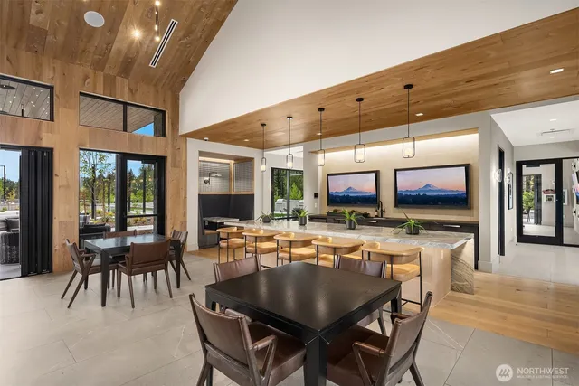 a dining hall with stainless steel appliances a dining table and chairs with the floor to ceiling window