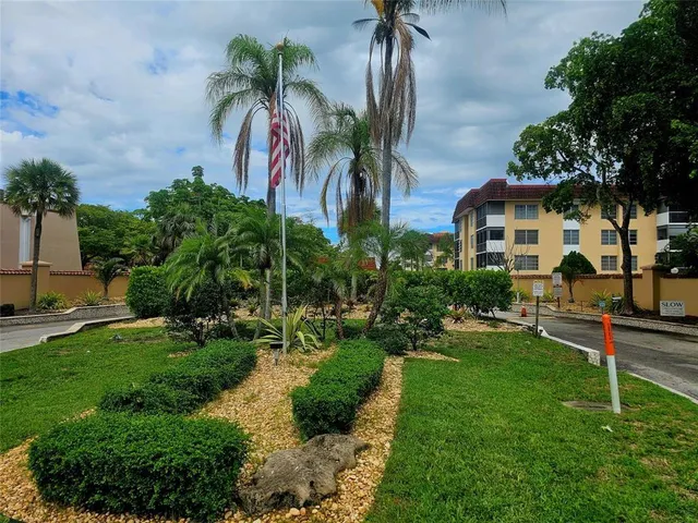 a front view of a house with a yard and palm trees