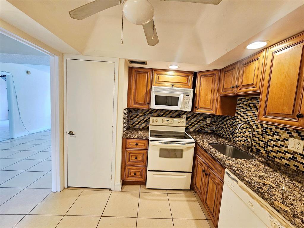 4172 Inverrary Drive, Unit 410 Lauderhill, FL 33319 - Photo 9 of 23 a kitchen with stainless steel appliances granite countertop a refrigerator and a stove top oven