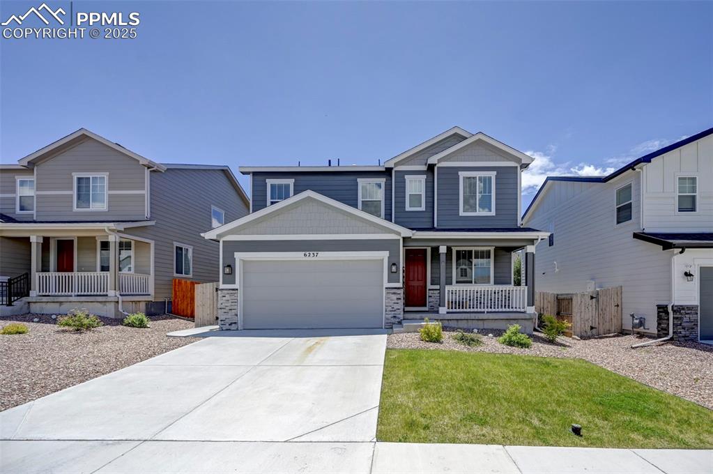 Craftsman-style house featuring covered porch, a garage, concrete driveway, and stone siding