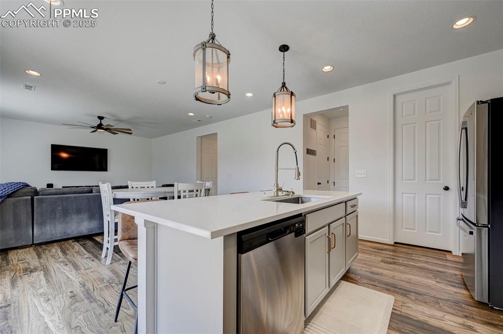 6237 Bodacious Circle Colorado Springs, CO 80923 - Photo 12 of 33 Kitchen with appliances with stainless steel finishes, ceiling fan, light wood finished floors, open floor plan, and a breakfast bar area