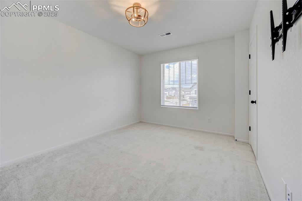 6237 Bodacious Circle Colorado Springs, CO 80923 - Photo 24 of 33 Unfurnished room featuring light colored carpet and a chandelier