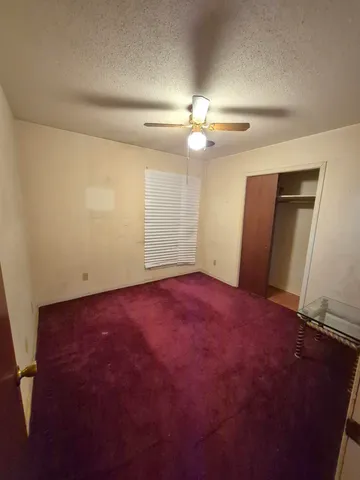 an empty room with windows and fan