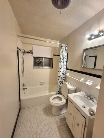 a bathroom with a granite countertop sink a toilet and shower