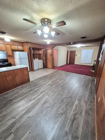 a view of a hallway with a large kitchen space in the back