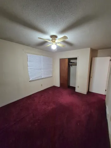an empty room with chandelier fan and windows
