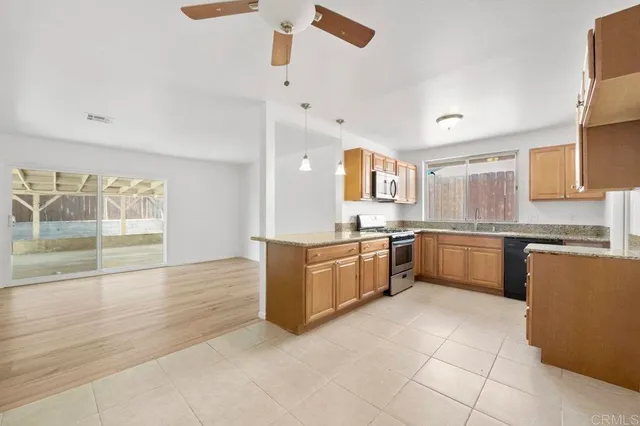 a large kitchen with granite countertop a large counter top space a sink stainless steel appliances and cabinets