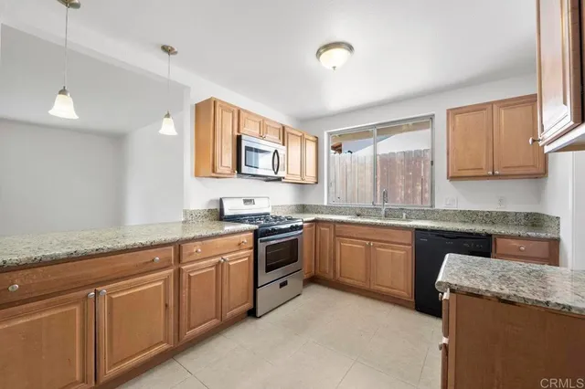 a kitchen with granite countertop cabinets stainless steel appliances a sink and a window