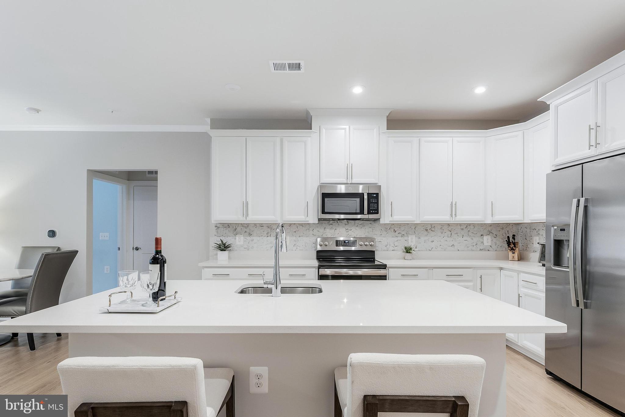 1675 Bandit Loop, Unit 105B Reston, VA 20190 - Photo 1 of 27 a kitchen with stainless steel appliances a sink a stove a refrigerator and white cabinets with wooden floor