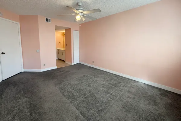 an empty room with a chandelier fan and windows