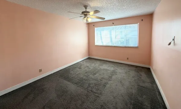 an empty room with windows and fan