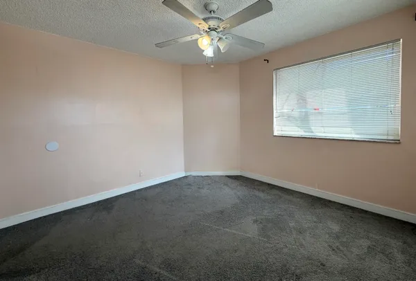 an empty room with a window and a fan