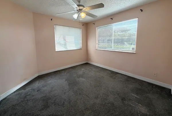 an empty room with windows and fan