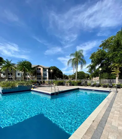 a view of a swimming pool with lawn chairs under an umbrella