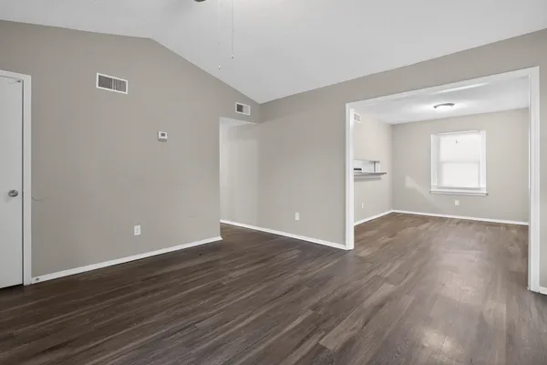 a view of an empty room with wooden floor and a window