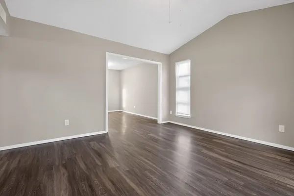 a view of an empty room with wooden floor and window