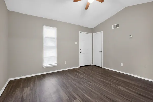 an empty room with wooden floor cabinet and windows
