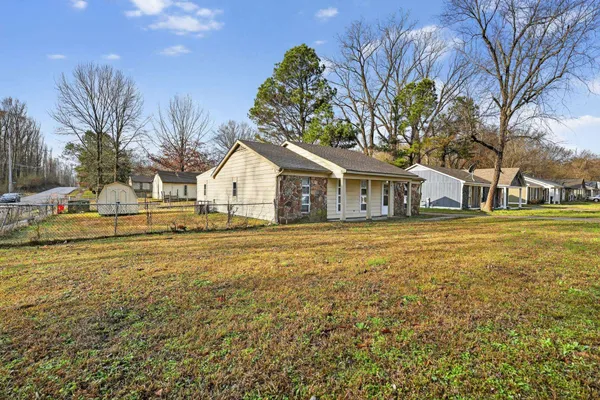 a white house with a big yard plants and large trees