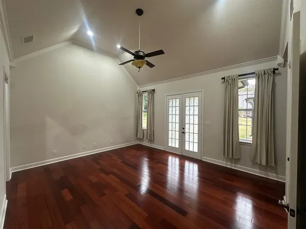 a view of an empty room with wooden floor and a window