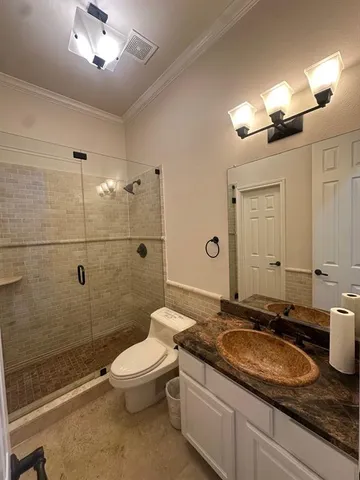 a bathroom with a granite countertop sink a toilet a mirror and shower