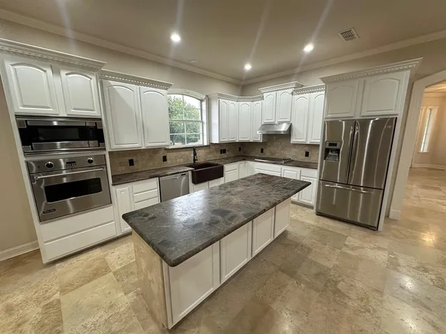 a kitchen with stainless steel appliances granite countertop a stove a sink and a refrigerator