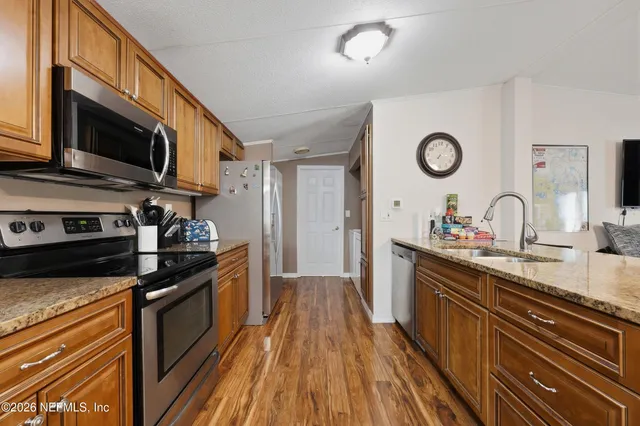 a kitchen with stainless steel appliances granite countertop a stove a sink and a microwave