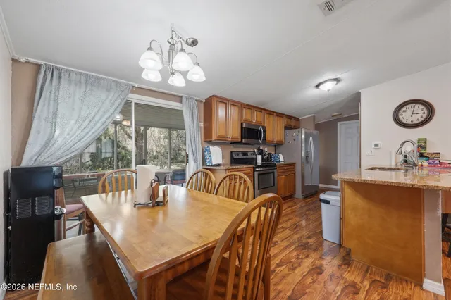 a dining room with wooden floor a chandelier a wooden table and chairs