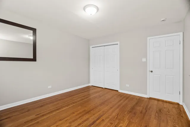 a view of an empty room with wooden floor and closet