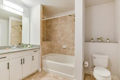 a bathroom with a granite countertop sink a toilet and shower