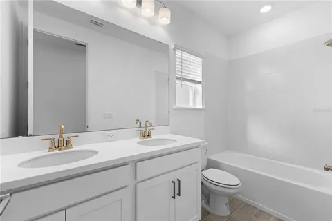 a bathroom with a toilet a sink a mirror a window and vanity