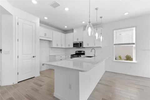 a large white kitchen with lots of counter space sink and appliances