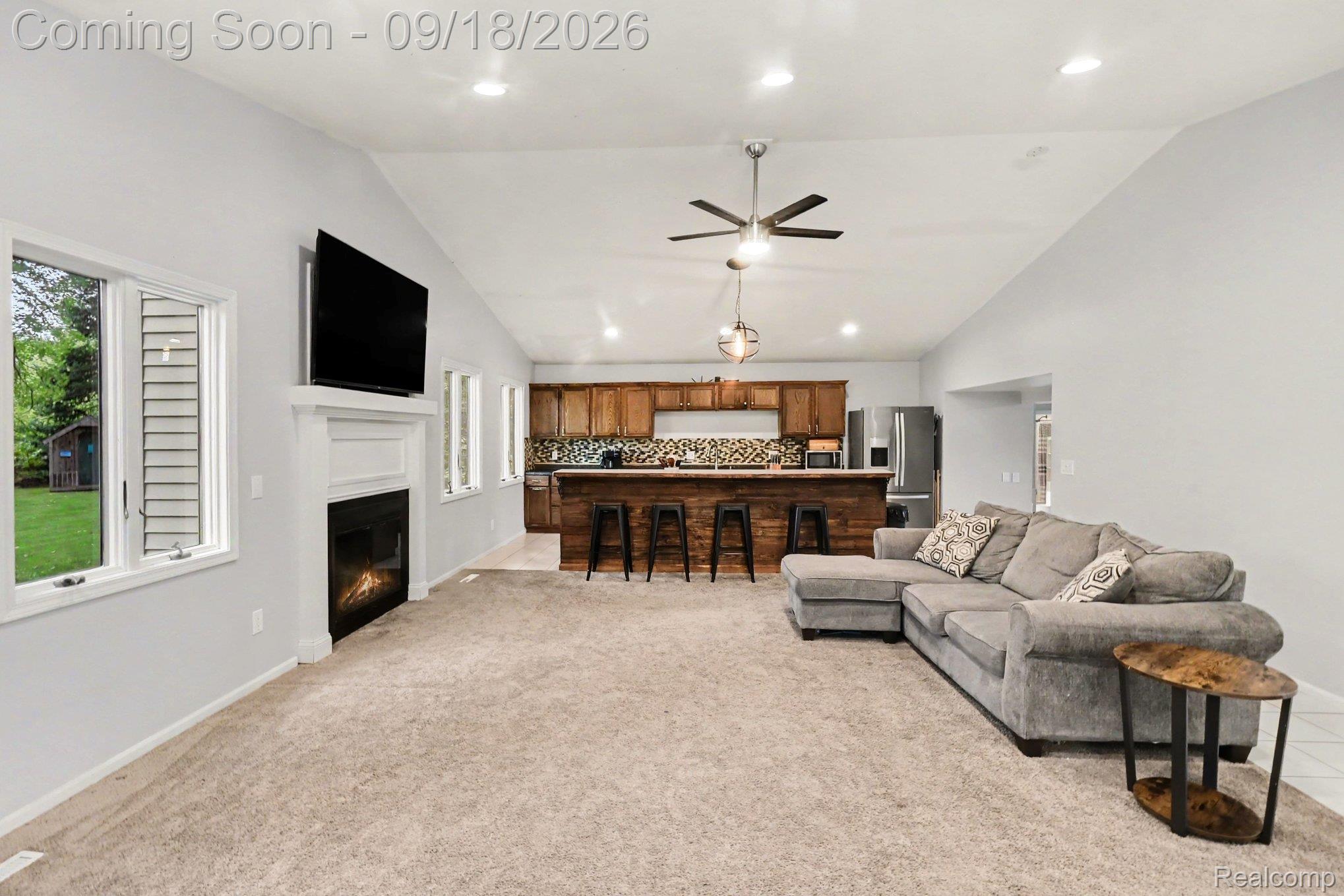 10755 Spencer Road St. Charles, MI 48655 - Photo 18 of 35 Vaulted ceiling with recessed lighting, fireplace with mantel, wood-finish kitchen cabinetry, kitchen island with seating, and stainless steel appliances