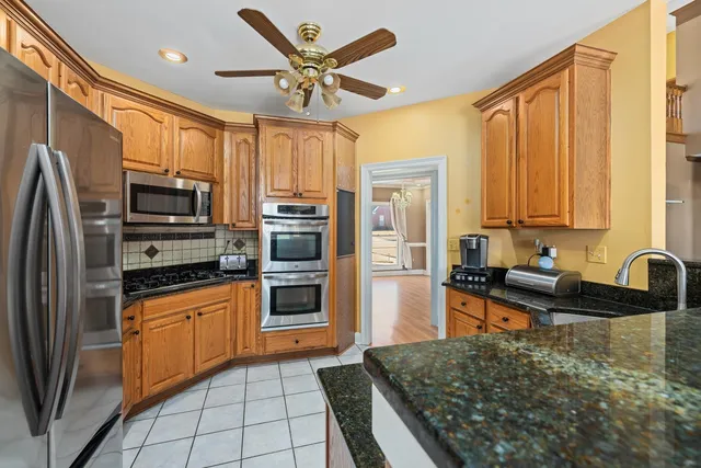 a kitchen with stainless steel appliances granite countertop a refrigerator a stove top oven and sink