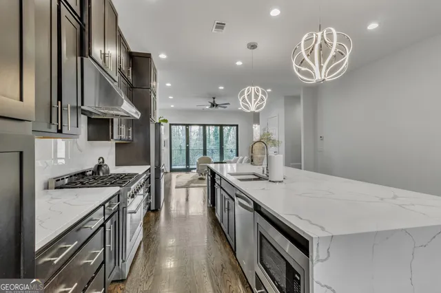 a kitchen with stainless steel appliances granite countertop a sink a stove and a wooden floors