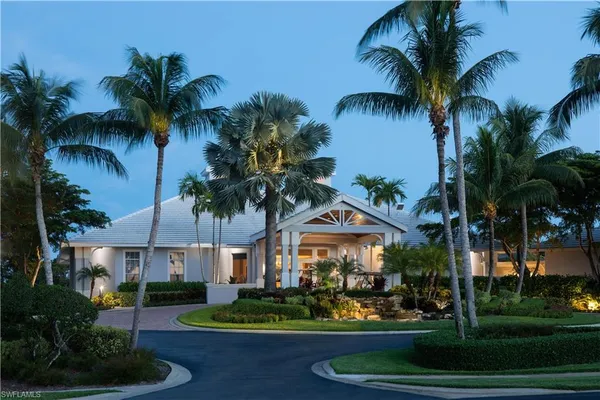 a view of a white house with a big yard and potted plants
