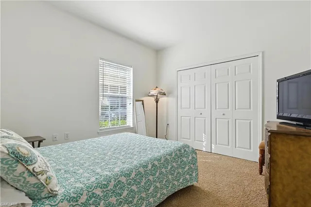 a bedroom with a bed and a flat tv screen on a dresser