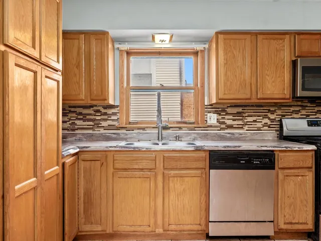 a kitchen with stainless steel appliances granite countertop wooden cabinets a sink and a window