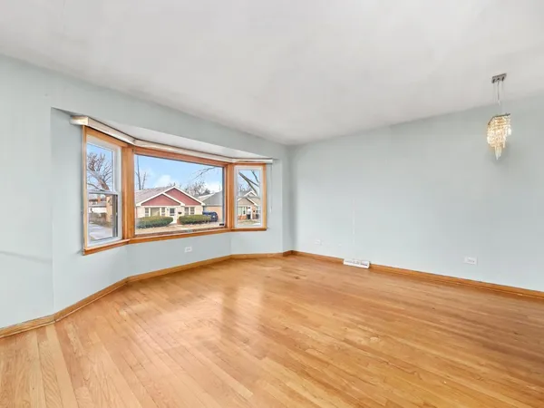 a view of an empty room with window and wooden floor