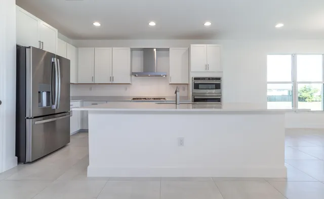 a kitchen with stainless steel appliances granite countertop a refrigerator a sink a stove and a refrigerator with wooden floor